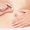 Entsyymivalmisteesta voi olla apua palkokasvien aiheuttamiin vatsavaivoihin Birth control pill, Contraceptive pills, Vitamin pill, pills for better digestion or pills against menstrual pain. Woman holding white tablet in front of stomach. Close up.